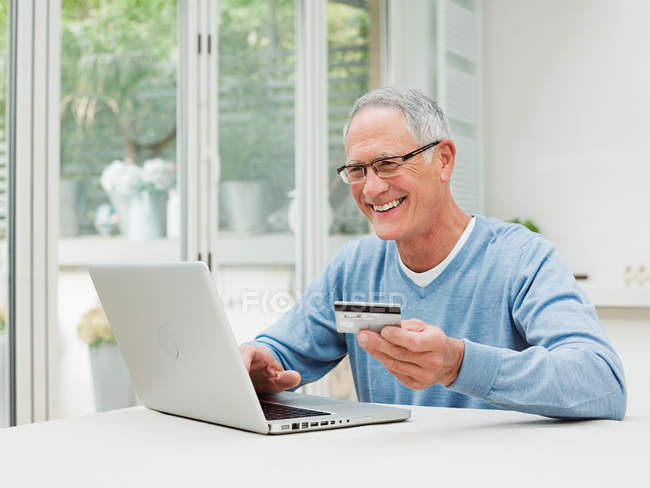Homme âgé utilisant un ordinateur portable avec carte de crédit — Photo de stock