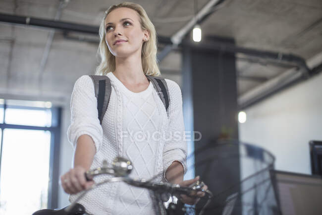 Young woman arriving with bicycle to office — Stock Photo