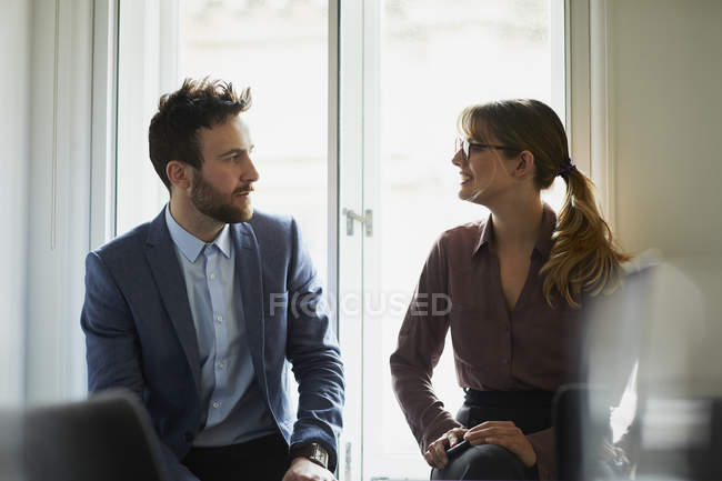 Два коллеги разговаривают лицом к лицу в офисе — стоковое фото