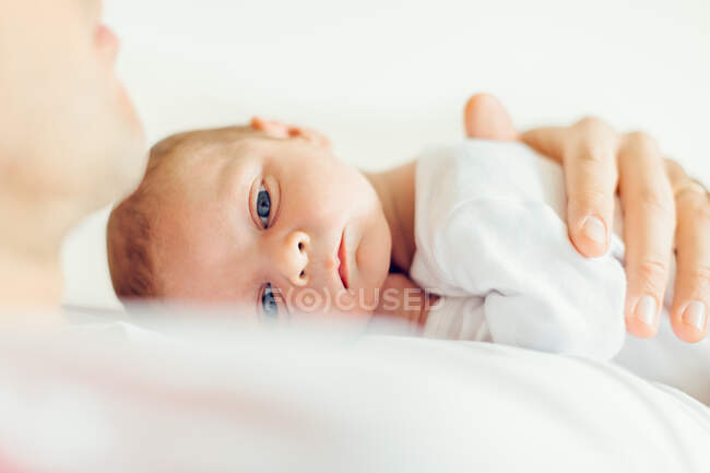 Bébé garçon couché sur la poitrine des pères regardant caméra — Photo de stock