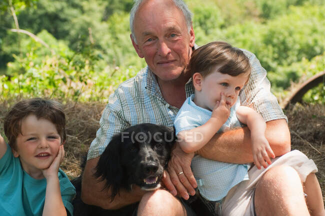 Grandfather with two grandsons and dog, portrait — Stock Photo