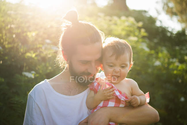 Hombre joven con niña en el jardín - foto de stock