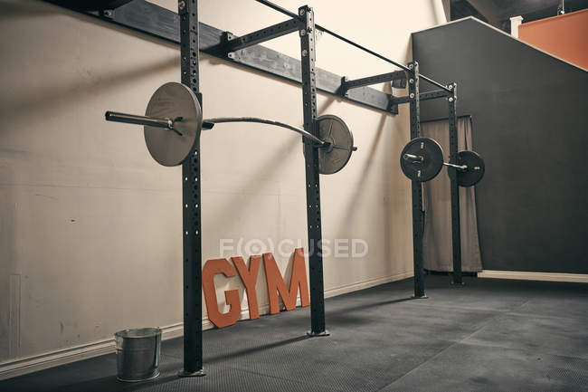 Barbells against white wall  in gym indoors — Stock Photo