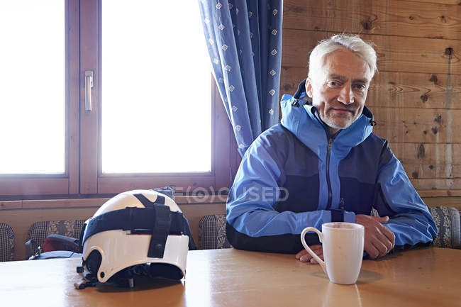 Hombre tomando un descanso para tomar café en la cabaña de troncos, Hintertux, Tirol, Austria - foto de stock