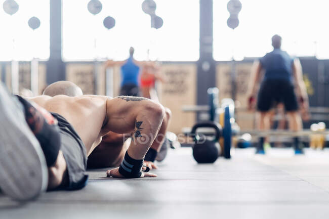 Cropped rear view of man doing push up on gym — Stock Photo