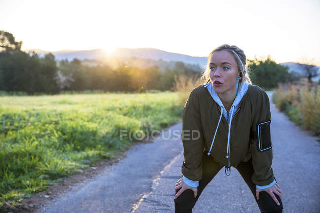 Young woman outdoors taking break from exercising — Stock Photo