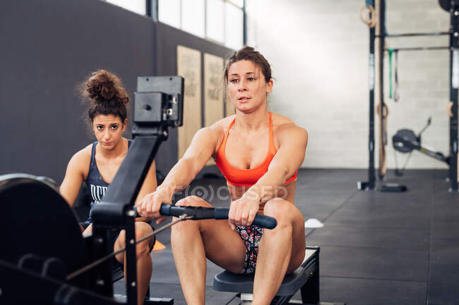 Mujeres en gimnasio usando máquina de remo - foto de stock