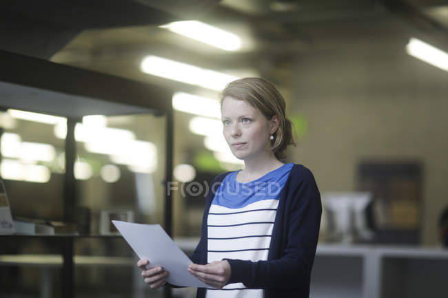 Mujer trabajadora de oficina sosteniendo documento - foto de stock