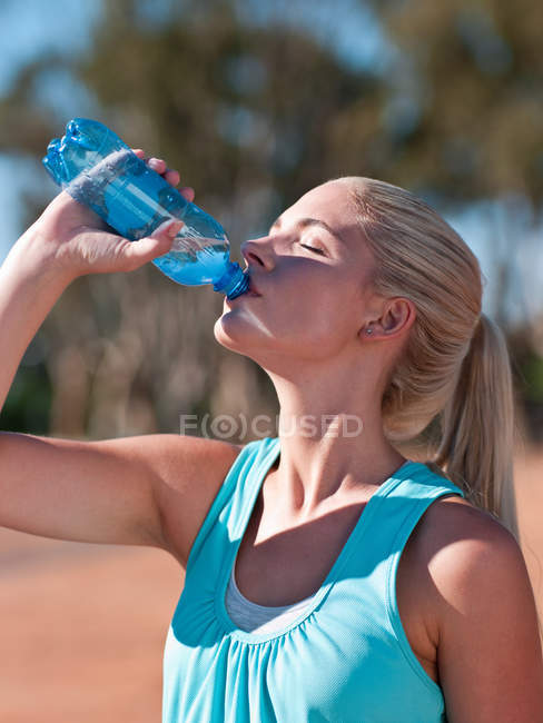 Jeune femme boire de l'eau minérale — Photo de stock