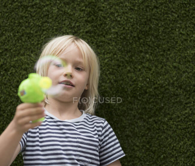 Вид спереду Хлопчик дме бульбашку з виробником бульбашок — стокове фото