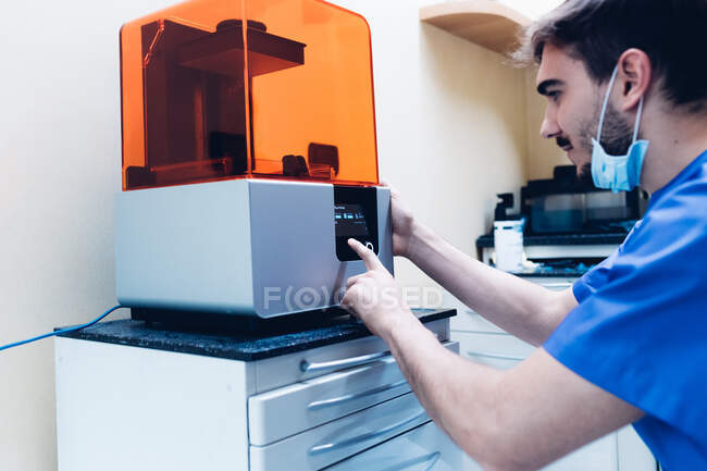 Dentista masculino usando impresora 3D - foto de stock