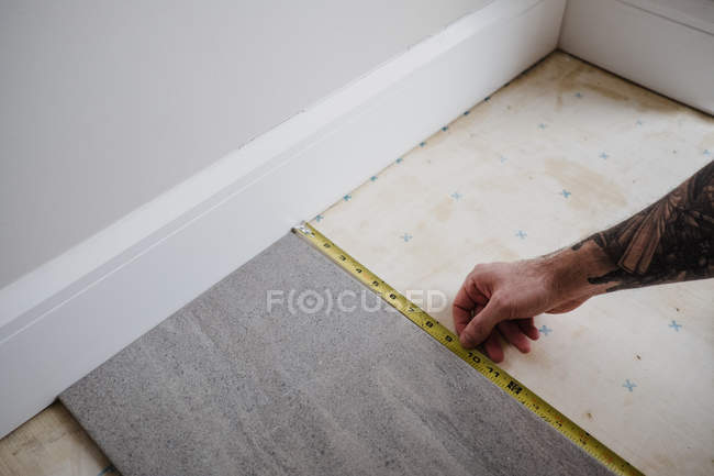 Vista ritagliata dell'uomo misurazione piastrelle del pavimento — Foto stock