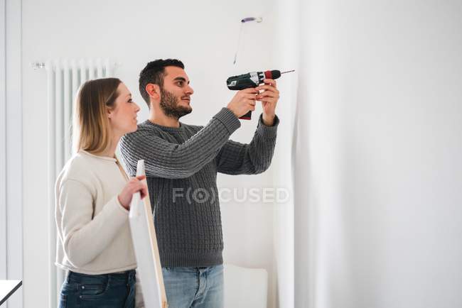 Paar bohrt Wand zum Aufhängen von Bild — Stockfoto