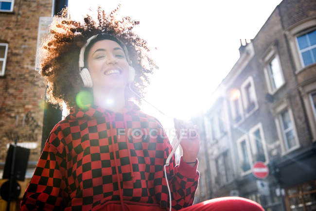 Молодая женщина в наушниках улыбается на улице — стоковое фото