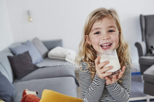 Retrato de menina na sala de estar segurando copo de leite — Fotografia de Stock