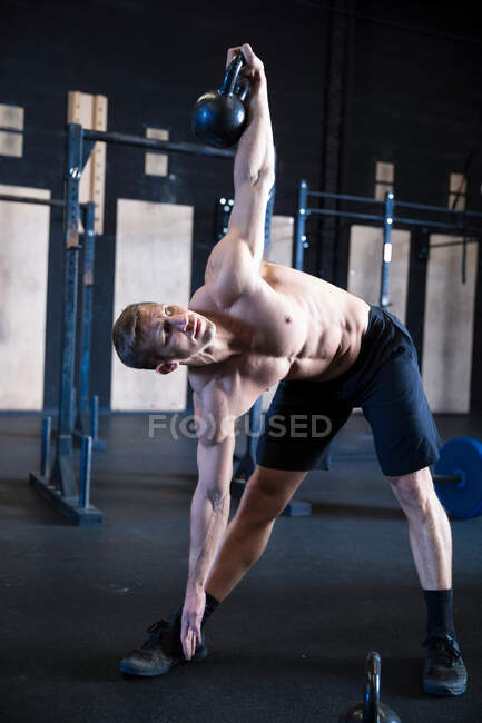 Man exercising in gymnasium, using kettlebell — Stock Photo