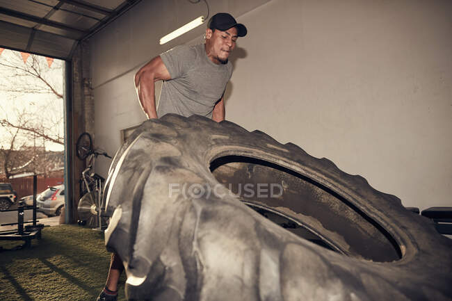 Homme soulevant gros pneu — Photo de stock