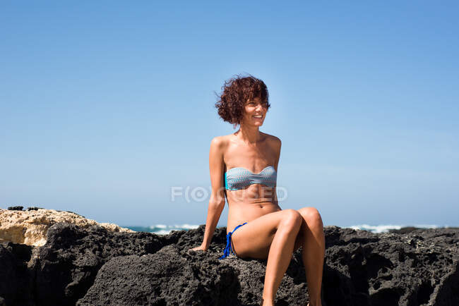 Donna seduta sulle rocce in riva al mare, Corralejo, Fuerteventura, Isole Canarie — Foto stock