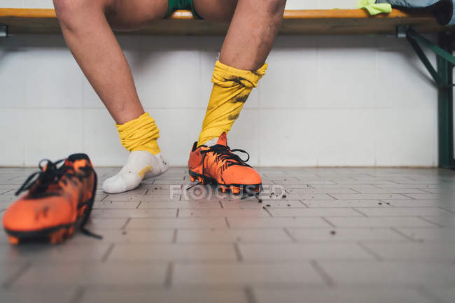 Жінка-футболістка в одному футбольному черевику в роздягальні — стокове фото