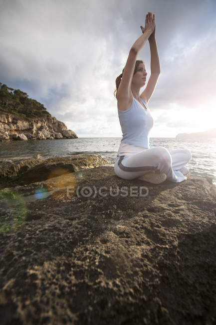 Donna seduta su rocce dal mare e meditando, Palma de Mallorca, Isole Baleari, Spagna, Europa — Foto stock
