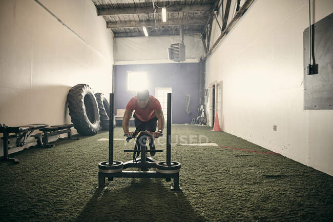 Homme dans la salle de gym en utilisant des équipements d'exercice — Photo de stock