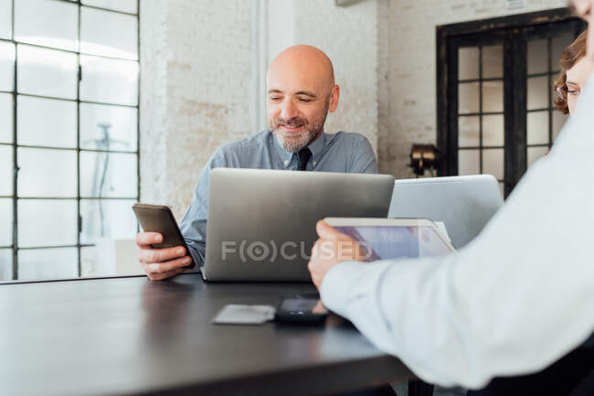 Geschäftsmann schaut lächelnd aufs Smartphone — Stockfoto