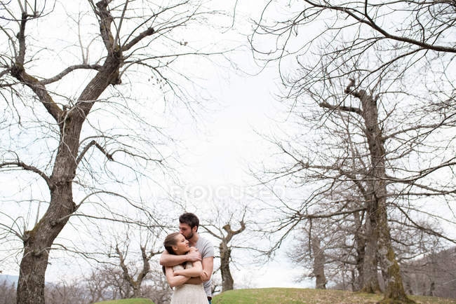 Мужчина обнимает женщину в парке — стоковое фото