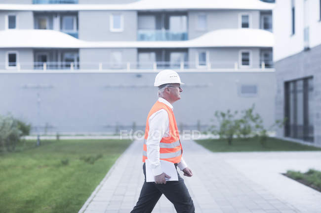 Seitenansicht eines erwachsenen Bauarbeiters, der am Gebäude vorbeigeht — Stockfoto