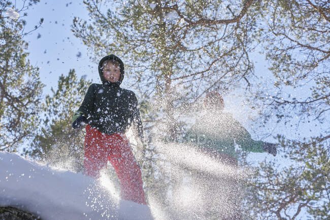 Dos chicos saltando en la nieve, vista de ángulo bajo - foto de stock
