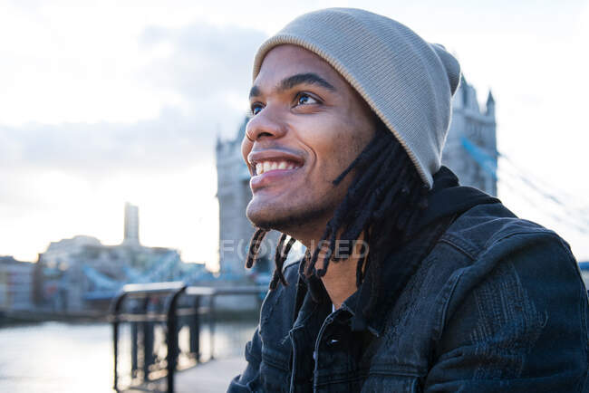 Retrato de un joven sentado al aire libre, sonriendo, Londres, Inglaterra, Reino Unido - foto de stock