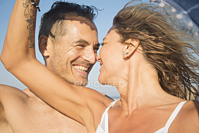 Coppia matura sulla spiaggia sorridente faccia a faccia — Foto stock