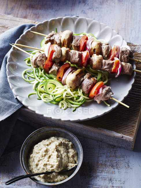 Lamb souvlaki skewers, with courgette noodles and baba ganoush, close-up — Stock Photo