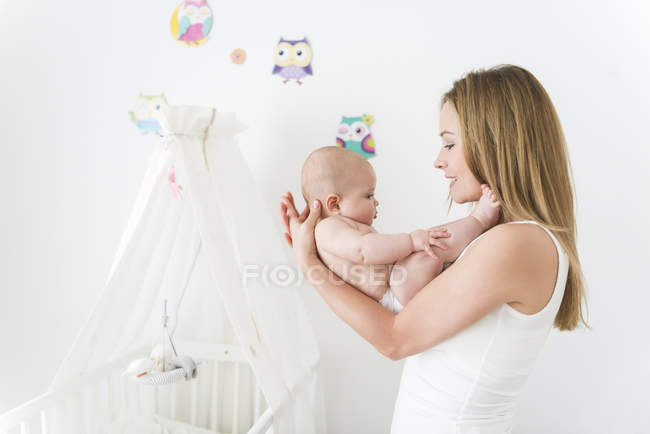 Mother cradling baby in nursery room — Stock Photo