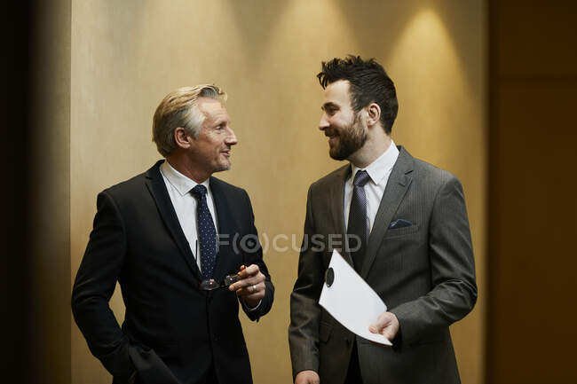 Два бизнесмена разговаривают в офисном коридоре — стоковое фото