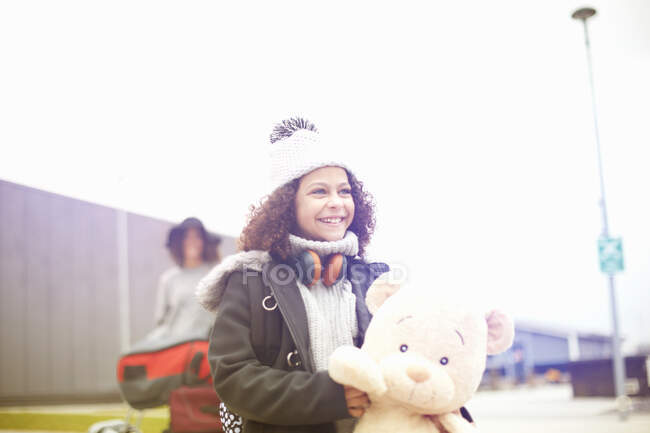 Портрет девушки, держащей плюшевого мишку, смотрящей в сторону улыбающейся — стоковое фото