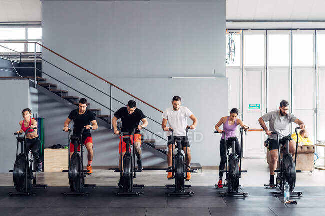 Люди в спортзалі використовують тренувальні велосипеди — стокове фото