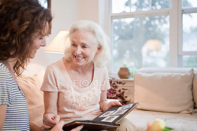 Mujer mayor y su hija con álbum de fotos - foto de stock