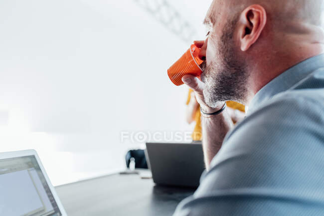 View over shoulder of man drinking from plastic cup — Stock Photo