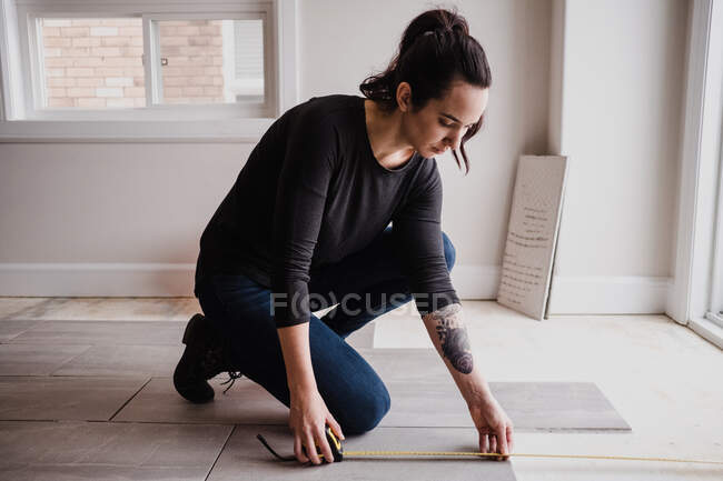 Женщина измеряет пол плитки — стоковое фото