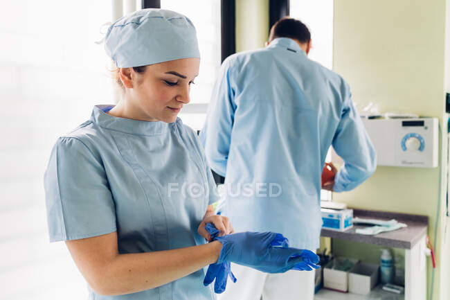 Odontoiatra in studio dentistico, indossare guanti chirurgici, dentista maschile in background — Foto stock