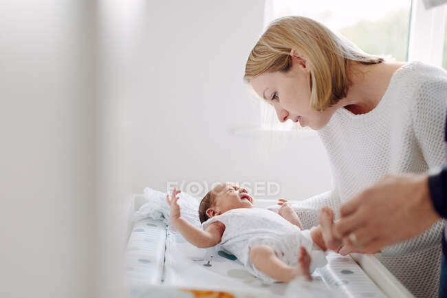 Madre y padre vistiendo bebé recién nacido - foto de stock