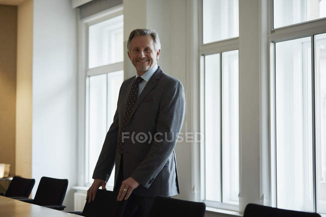 Портрет бизнесмена в офисе, улыбающегося в камеру — стоковое фото