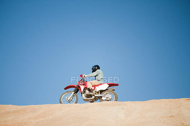 Seitenansicht eines Mannes auf einem Dirt-Bike auf einem Hügel — Stockfoto
