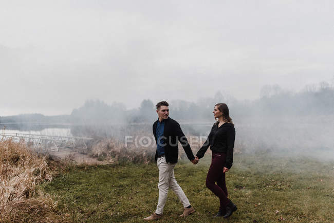 Jeune couple tenant la main marchant sur une prairie brumeuse, Ottawa, Canada — Photo de stock