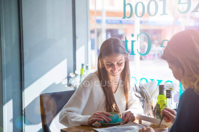 Two female friends sitting together in cafe, drinking coffee — Stock Photo