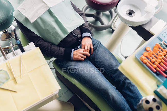 Paciente masculino en silla de dentista, sección media, vista elevada - foto de stock