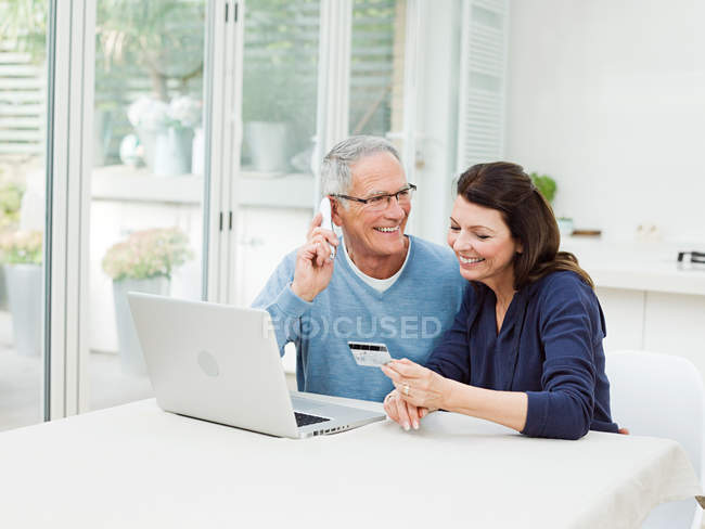Casal maduro usando laptop e cartão de crédito — Fotografia de Stock