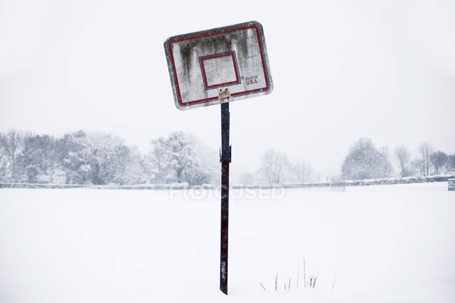 Broken basketball hoop on snowy square — Stock Photo