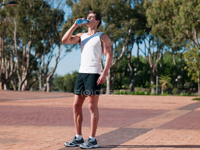 Молодий чоловік п'є мінеральну воду — стокове фото