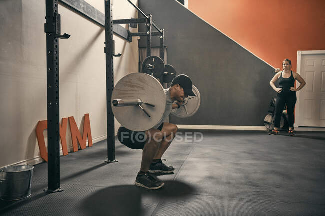 Man in gym weightlifting using barbell — Stock Photo